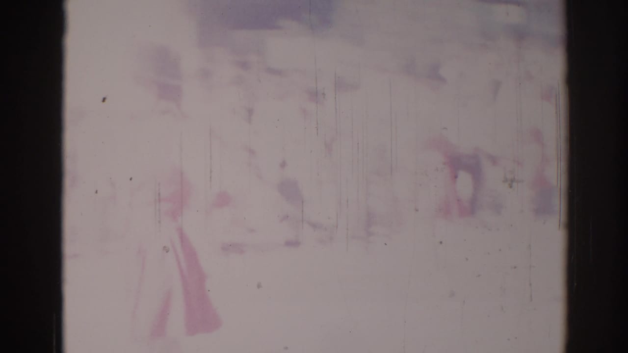 A faint person appears near a pale vehicle shape in washed-out 1967 Los Angeles home-movie footage.