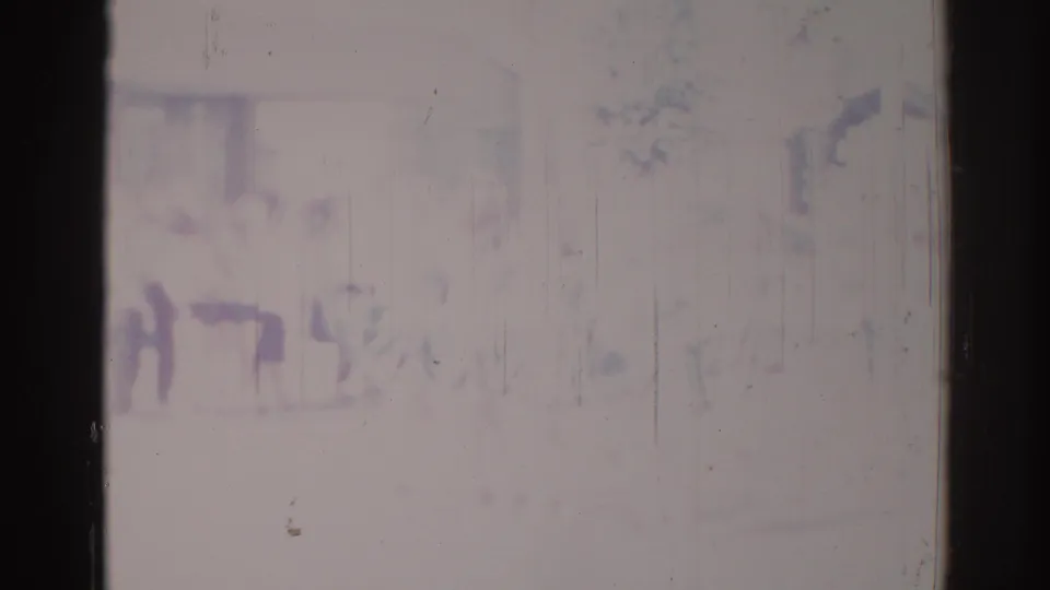 Faded 1967 Los Angeles 8mm frame showing a soft, distant view of people in formation near an urban facade.