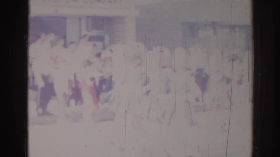 Faded 1967 Los Angeles home-movie frame showing a larger formation of people in light clothing moving past the camera.