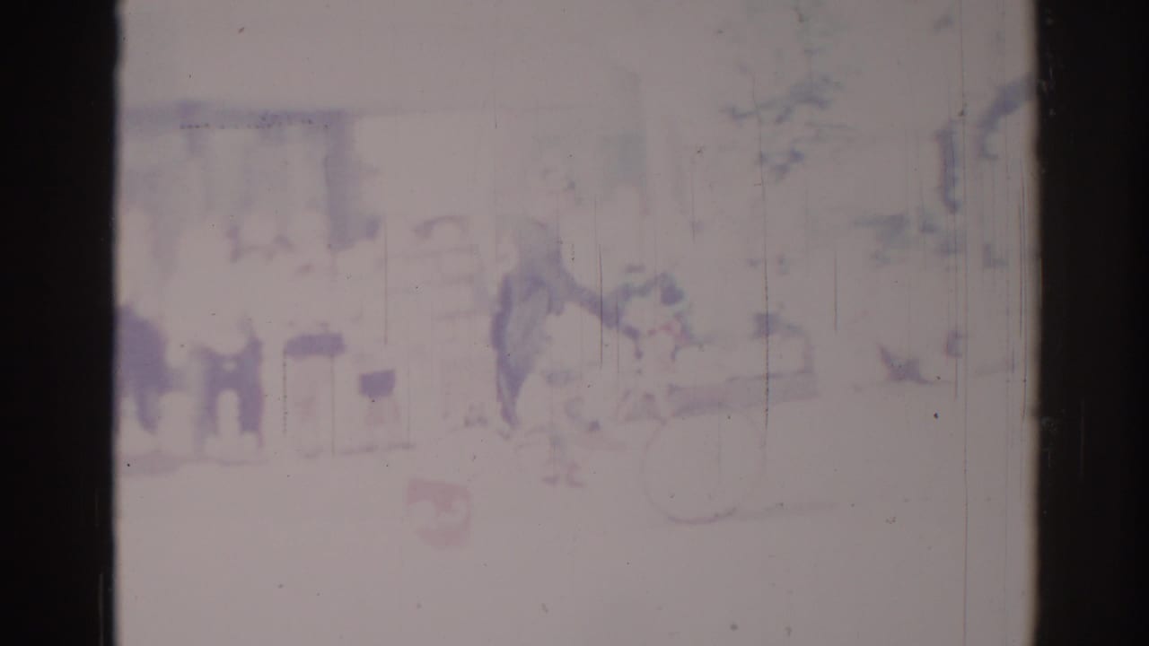 Faint urban street view with a bicyclist and indistinct figures in bright daylight.