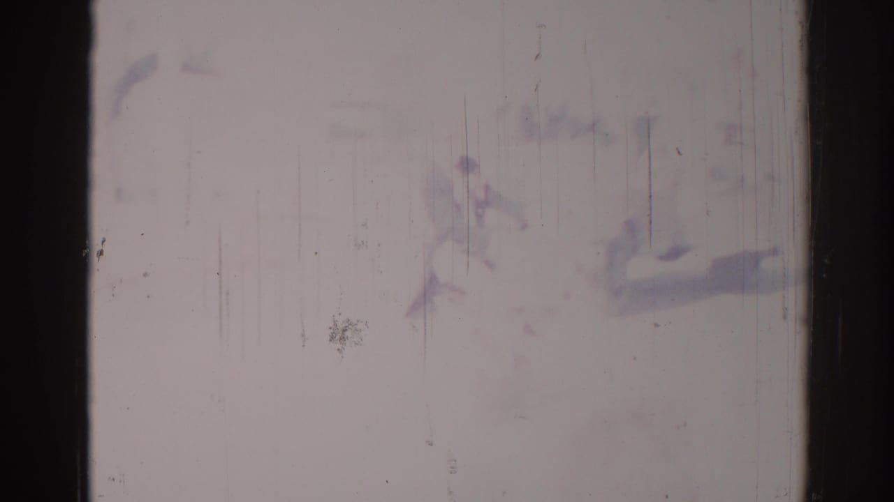 1967 Los Angeles street frame with pale exposure, faint figures, and urban forms partly obscured by film wear.