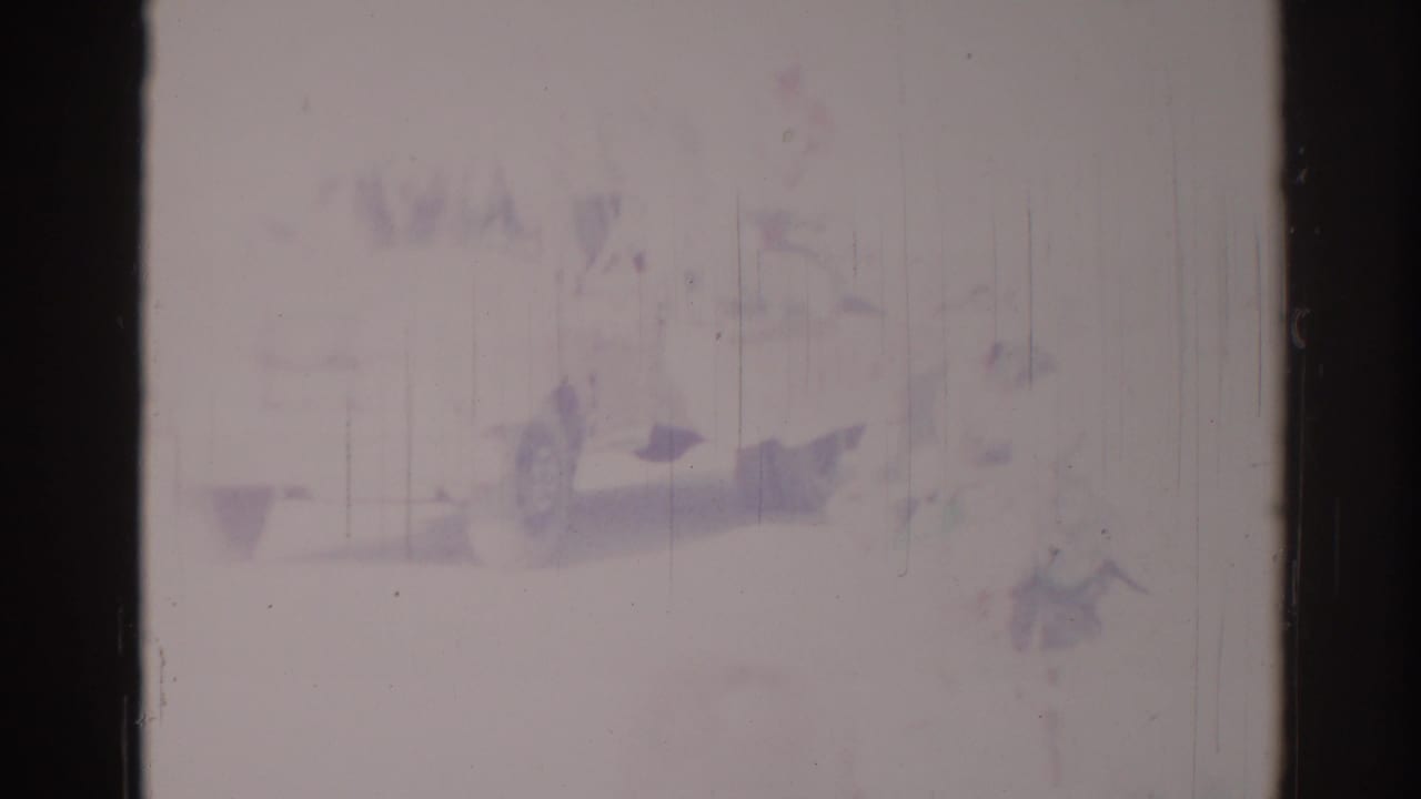 Faded 8mm frame from the Los Angeles clip, showing a barely defined bicyclist or rider shape within a bright street scene.