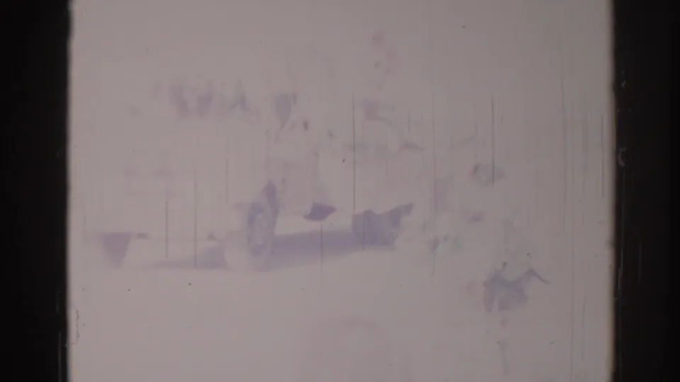 Faded 8mm frame from the Los Angeles clip, showing a barely defined bicyclist or rider shape within a bright street scene.