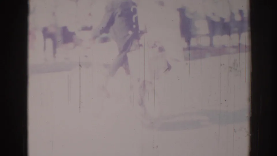 Blurry 1967 Los Angeles 8mm frame showing indistinct dark figures and bright stage-like forms with scratches and washed color.
