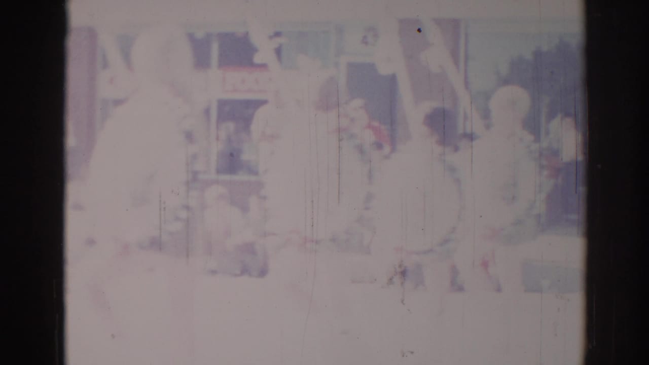 Overexposed 1967 Los Angeles home-movie frame with a faint performer-like figure and indistinct stage or room details.