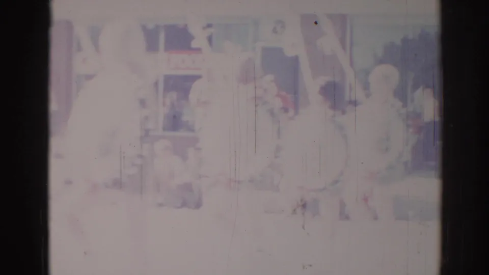 Overexposed 1967 Los Angeles home-movie frame with a faint performer-like figure and indistinct stage or room details.