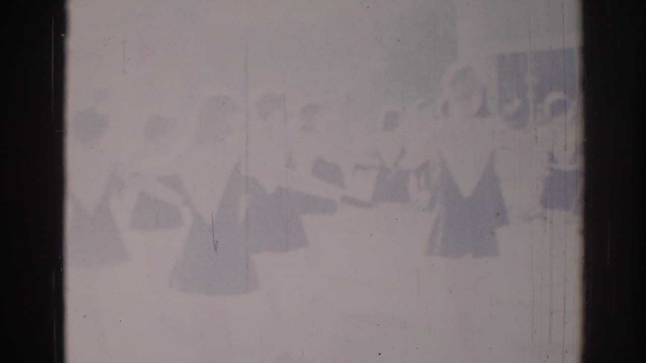 1967 Los Angeles 8mm frame showing a distant synchronized dance group in dark-and-light costumes, softened by exposure and film wear.