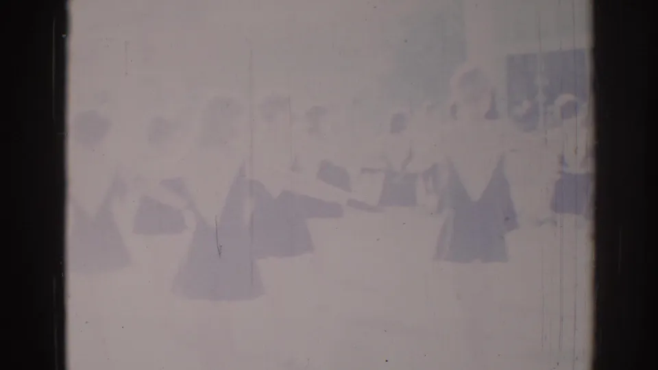 1967 Los Angeles 8mm frame showing a distant synchronized dance group in dark-and-light costumes, softened by exposure and film wear.