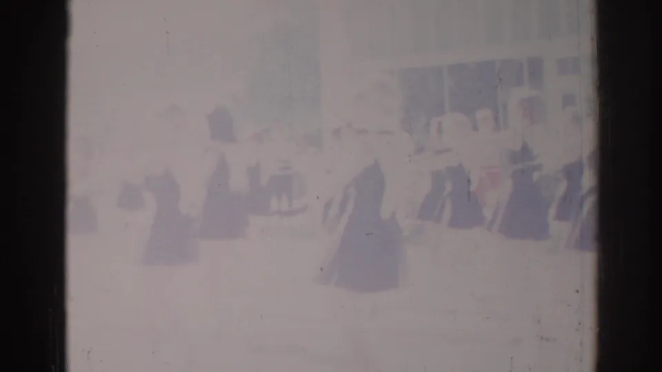Washed-out 8mm frame from the Los Angeles clip showing synchronized dancers spaced across a bright performance area.