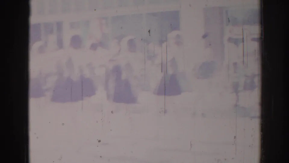 Soft 1967 Los Angeles home-movie frame with dancers in coordinated dress near a bright building or courtyard backdrop.