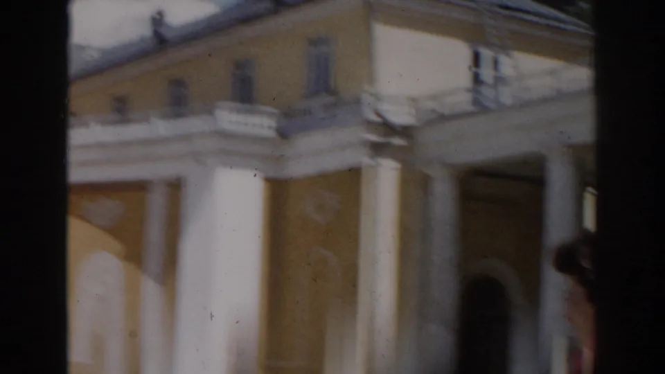 Soft 8mm frame from Moscow in 1968 showing the yellow building from a closer angle with balcony rails and white columns.