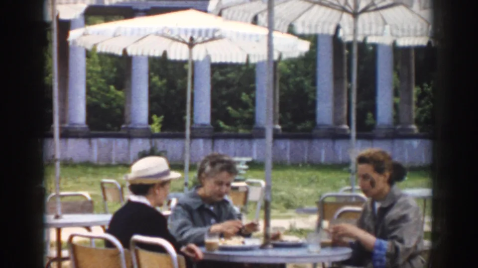 1968 Moscow outdoor cafe scene with three women seated at a table under striped umbrellas, with plates and glasses visible.