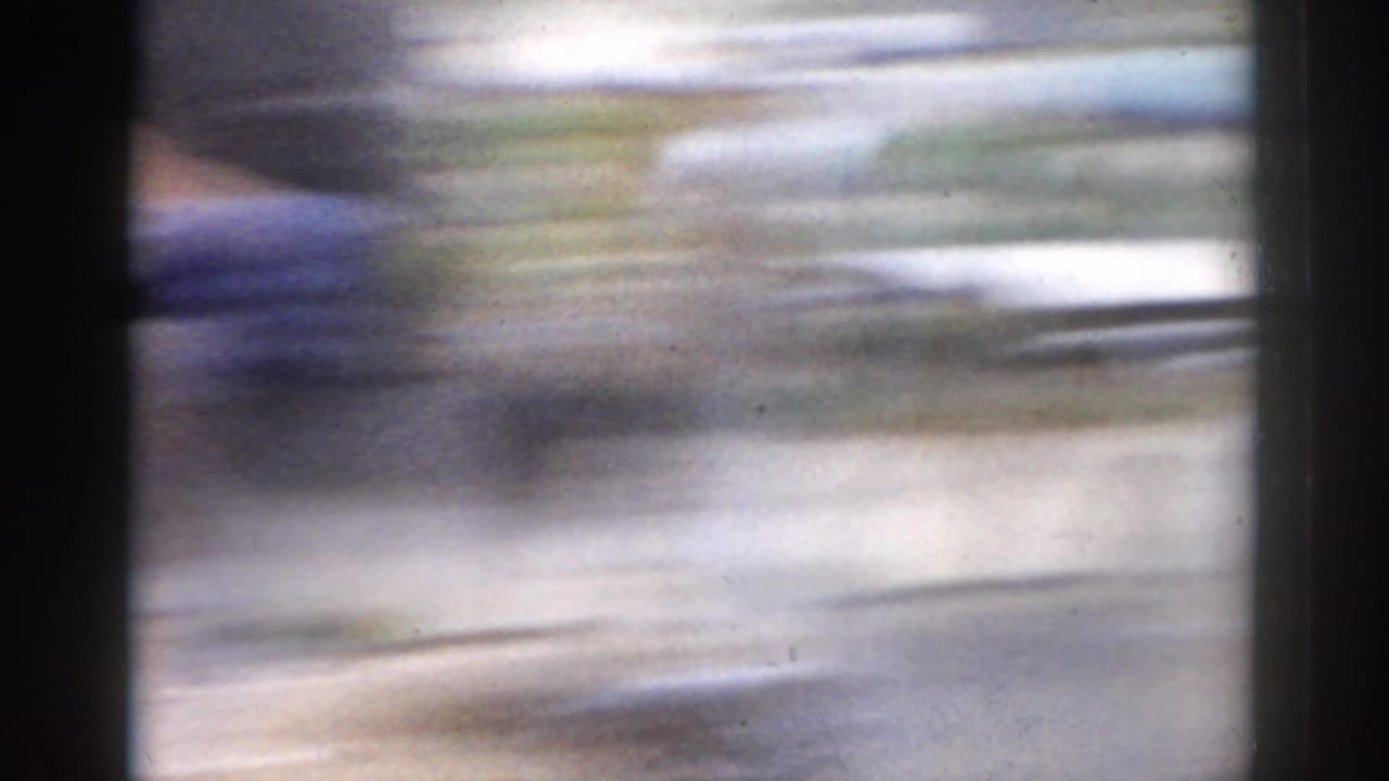 Soft, blurred opening frame from an 8mm home movie, with lateral motion and dark frame edges obscuring the scene.