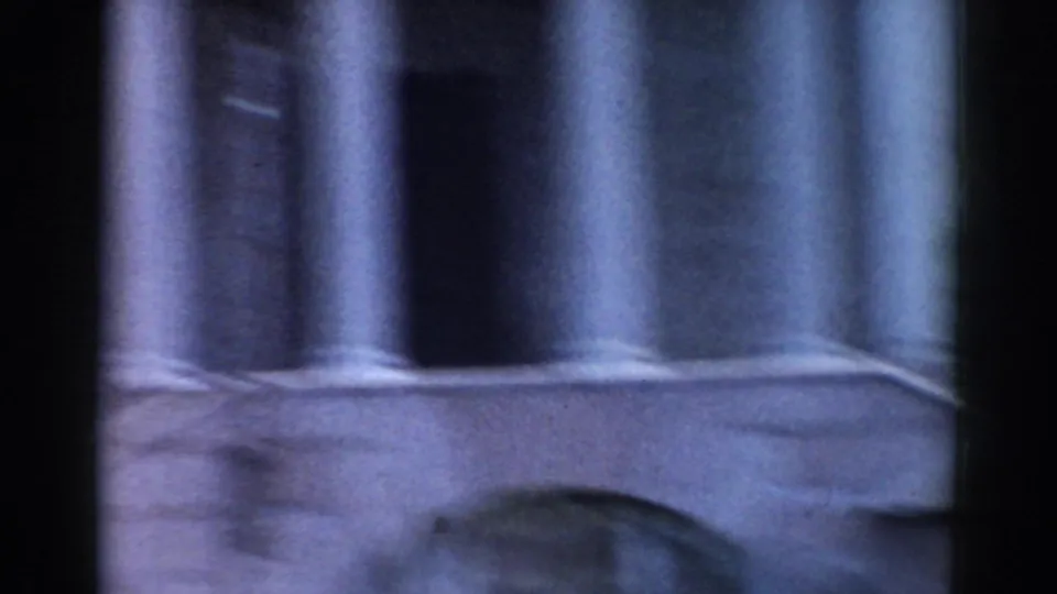 1968 Moscow home-movie frame showing fluted columns and a partial arched stone facade in soft, faded color.