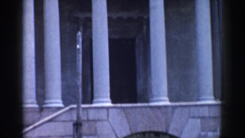 1968 Moscow frame showing tall columns, a stone base, and a shadowed doorway on a grand classical building exterior.