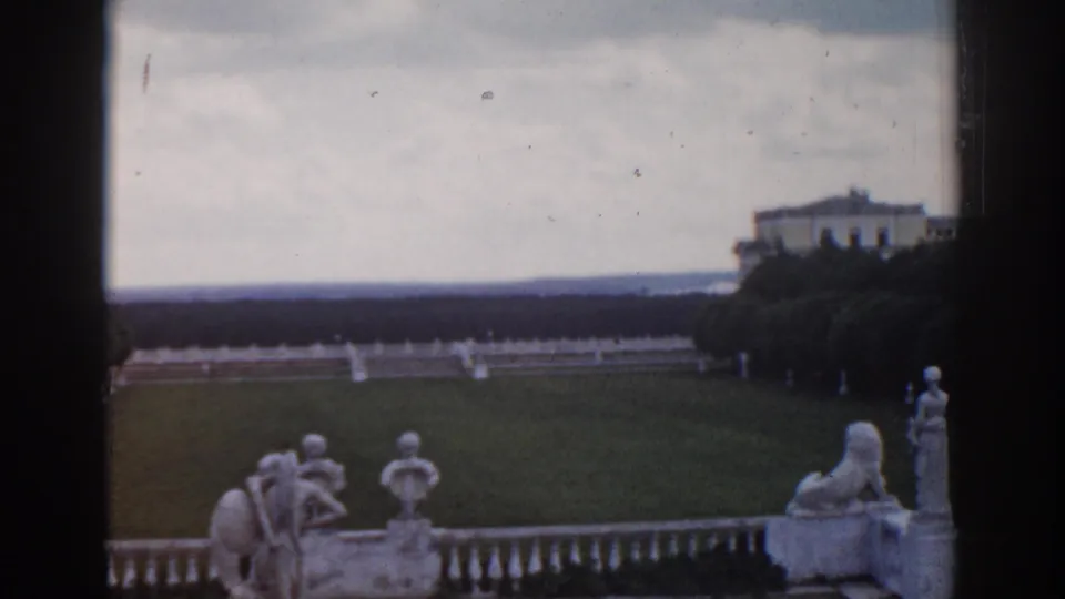 1968 Moscow 8mm still with terrace sculpture, balustrade, broad lawn, clipped trees, and a pale palace building in the distance.