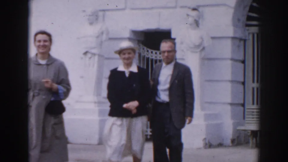 Two women and a man pose near a pale Moscow building facade, with steps, doorway details, and period clothing visible.