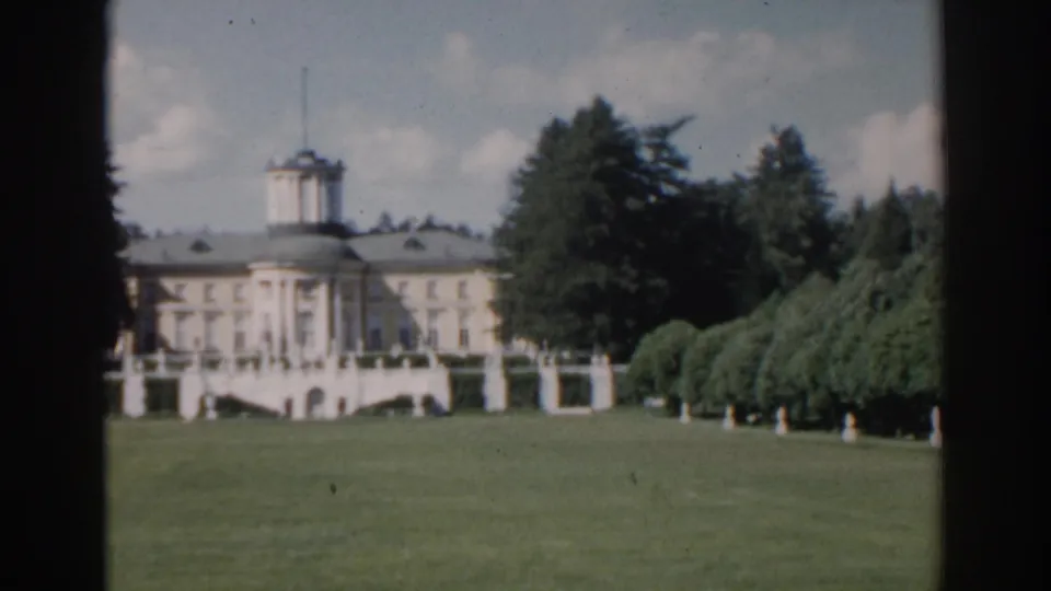 1968 Moscow 8mm frame showing a pale classical building, green lawn, trees, and dark window-like borders.