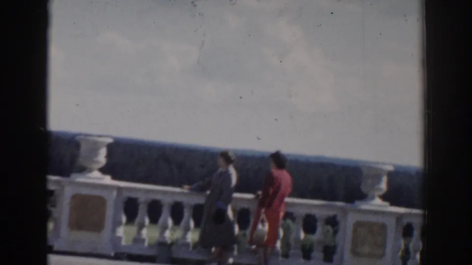A closer 1968 Moscow frame shows two women walking along the terrace beside the white balustrade, with soft 8mm blur and grain.