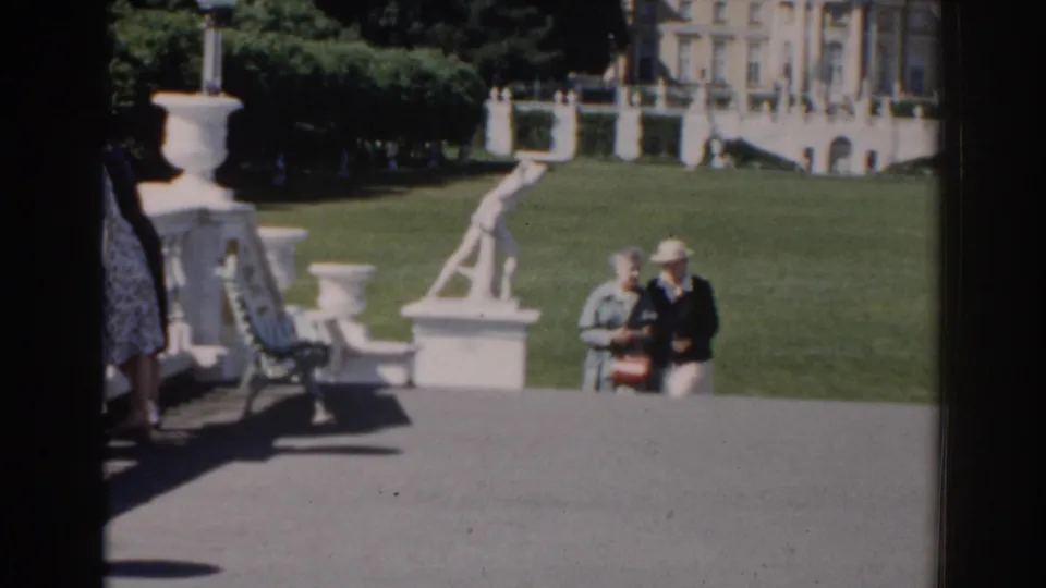 1968 Moscow park footage showing two women near the terrace, with white balustrade details, lawn, trees, and a palace-like building in the background.