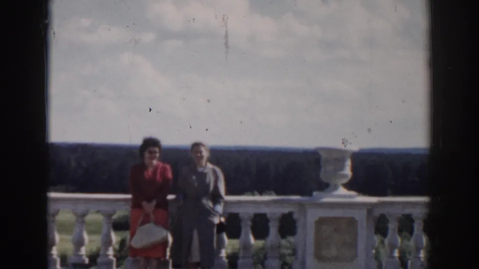 Two women in 1968 Moscow footage pose beside a pale stone balustrade overlooking a broad forested landscape.