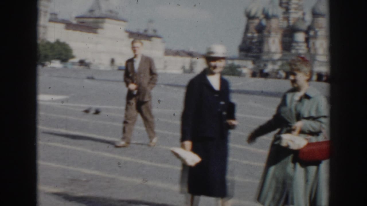 1968 8mm frame of an older couple crossing Red Square in Moscow, with St. Basil's Cathedral and pigeons visible in the background.