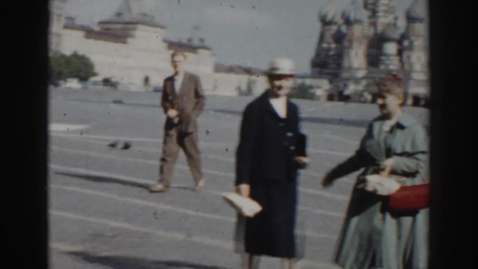 1968 8mm frame of an older couple crossing Red Square in Moscow, with St. Basil's Cathedral and pigeons visible in the background.