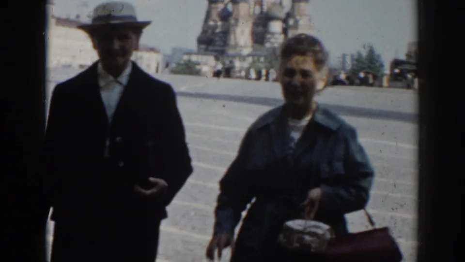 The older couple approaches the camera in Red Square, partially silhouetted against the bright pavement and cathedral backdrop.