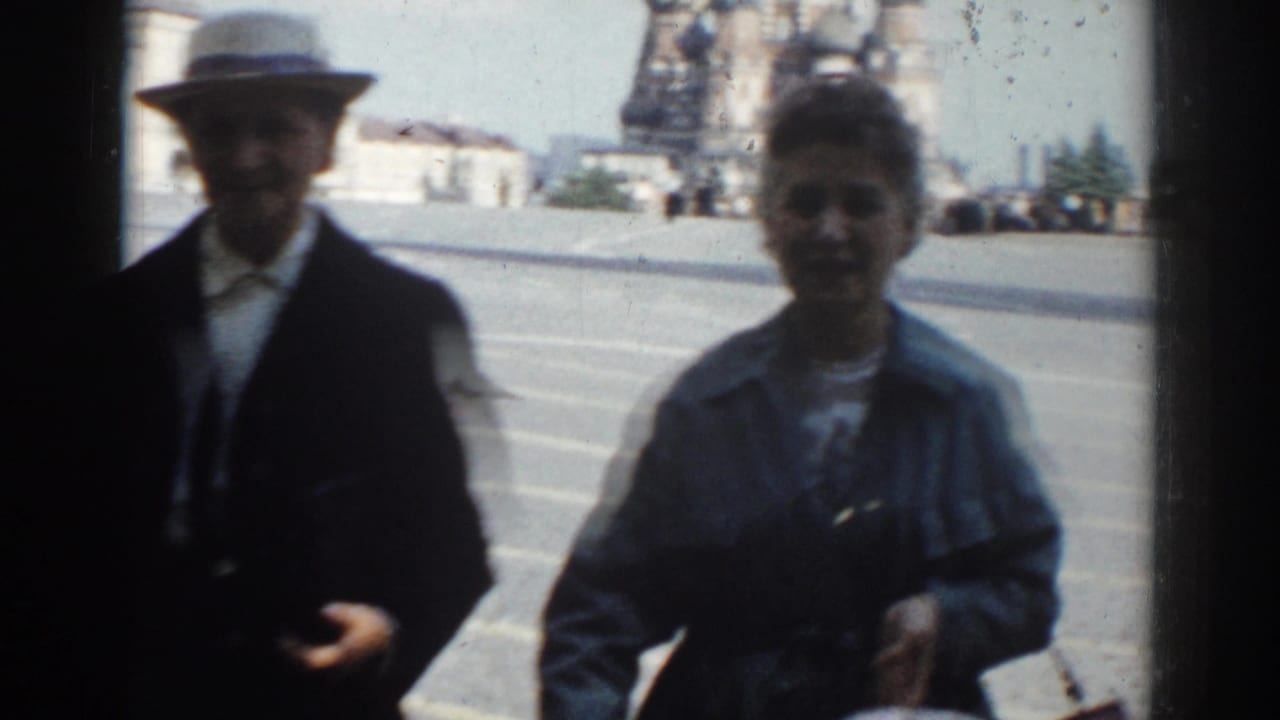 In 1968 Moscow home-movie footage, a suited man in a light hat and a woman with a bag appear close to camera near a public square.