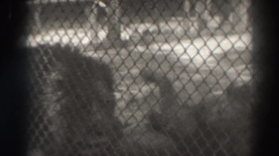 A soft black-and-white frame from the 1937 El Monte zoo visit shows an indistinct animal behind chain-link fencing.