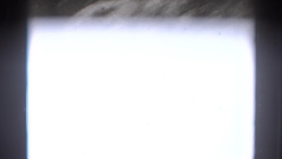 An overexposed section of the 8mm footage shows little detail beyond dark borders and a faint enclosure edge.