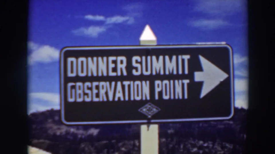 1937 8mm view of the Donner Summit Observation Point sign, with white lettering, a right arrow, and blue sky behind it.