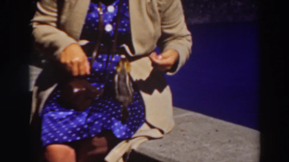 A 1937 Lake Tahoe home-movie frame shows a seated woman holding food as a small animal reaches near her lap.