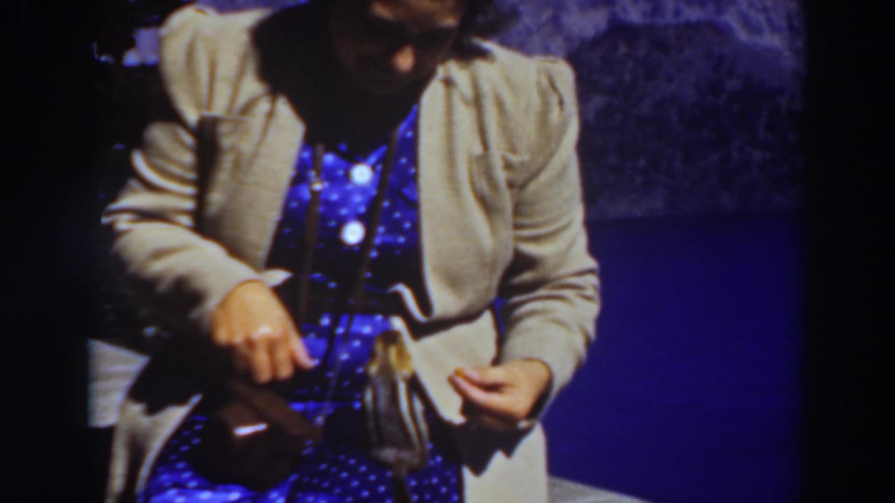 Woman in a beige sweater feeding a chipmunk on her lap.