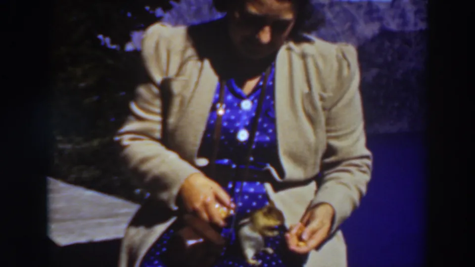 A 1937 Lake Tahoe home-movie frame shows the woman holding food as the small chipmunk stays close beside her hands.
