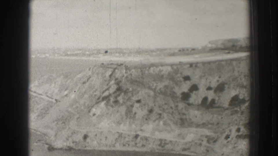 1937 8mm view of coastal bluffs near the Long Beach and Palos Verdes area, with ocean and distant shoreline on the horizon.