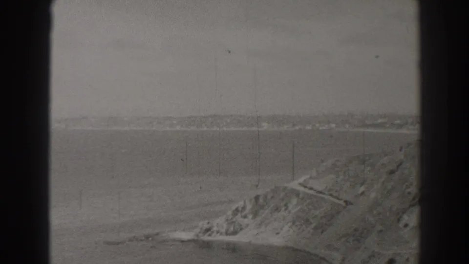 1937 Long Beach coastal view with calm water in the foreground, a bluff at right, and a path along the slope.