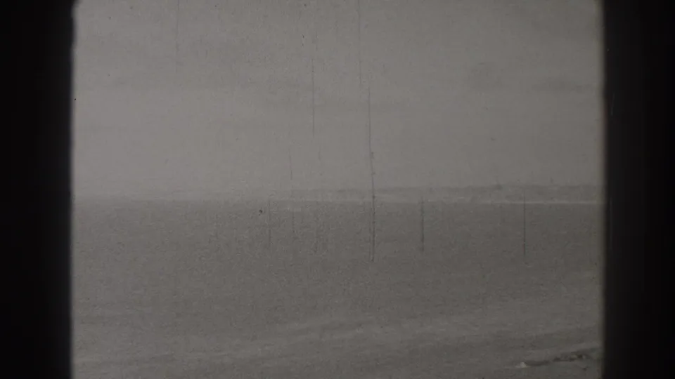 1937 8mm view over Long Beach, California, with ocean horizon, sandy foreground, and dark gate edges.