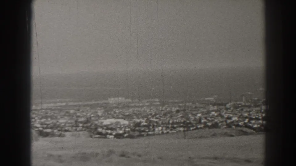 1937 Long Beach appears as a hazy coastal cityscape with the ocean beyond, viewed through dark foreground bars.