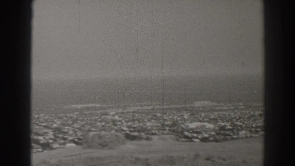 Long Beach city blocks sit beyond a foreground hillside, with the ocean horizon softened by haze and film grain.