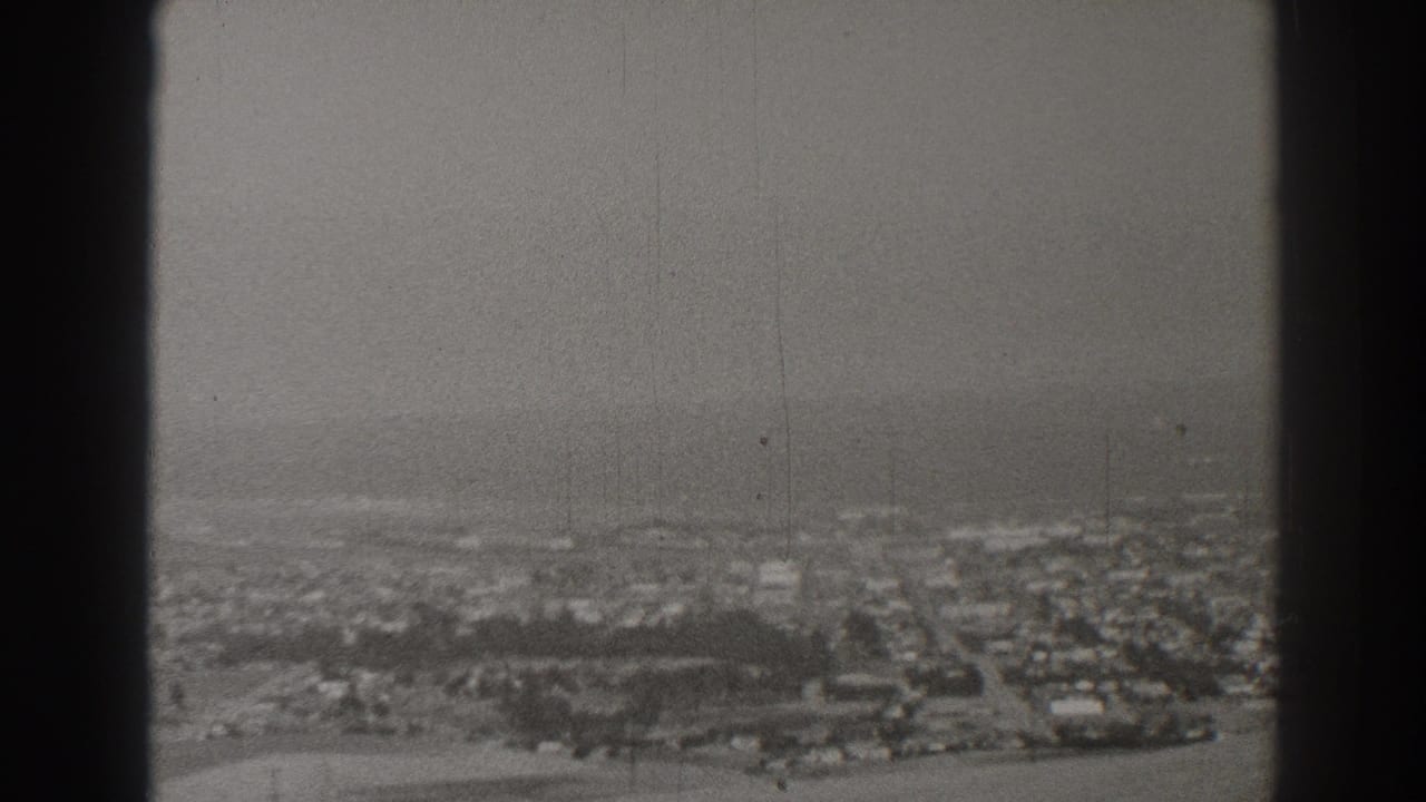 Distant townscape with houses, roads, trees, and dark film borders.