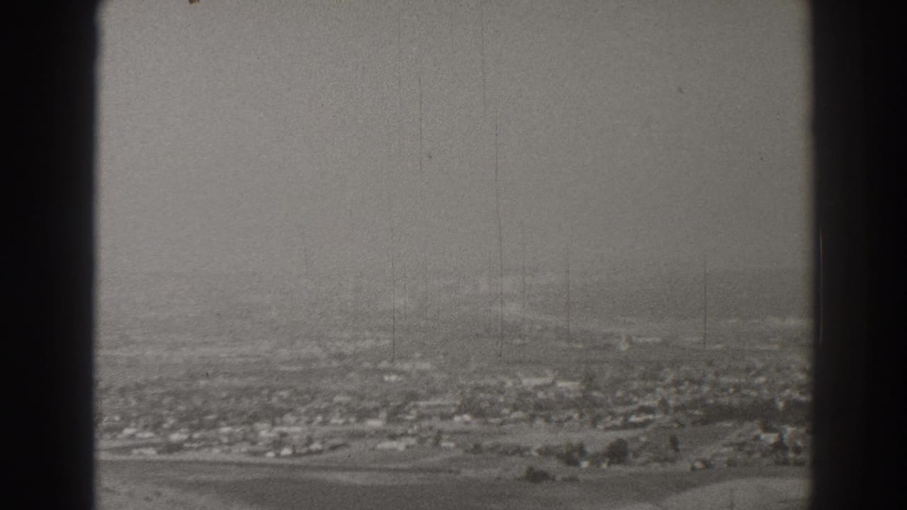 Hazy aerial view of a low-rise city seen through dark window framing.