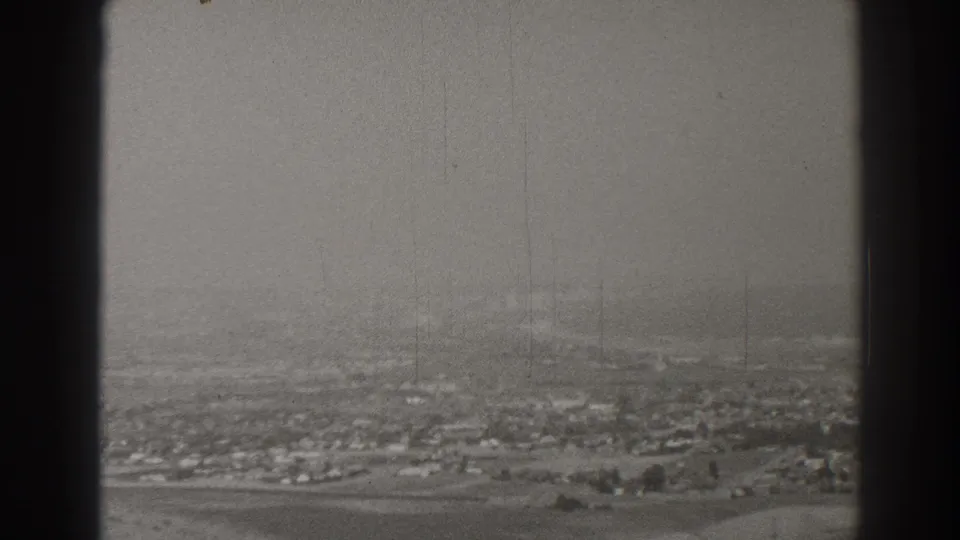 1937 Long Beach aerial view with scattered buildings, open land, and a dark vertical window frame at the left edge.