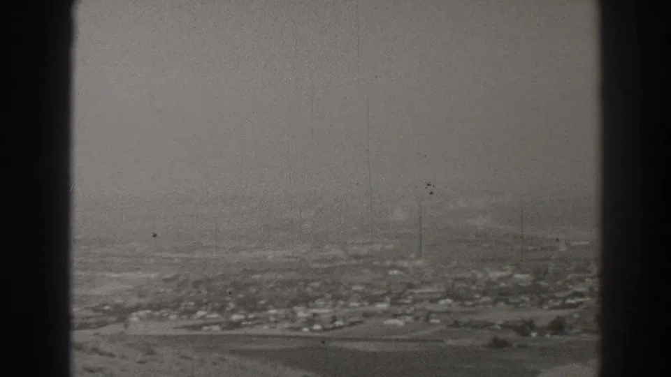 Hazy 1937 Long Beach aerial view with low buildings, open ground, and a central dark window frame.