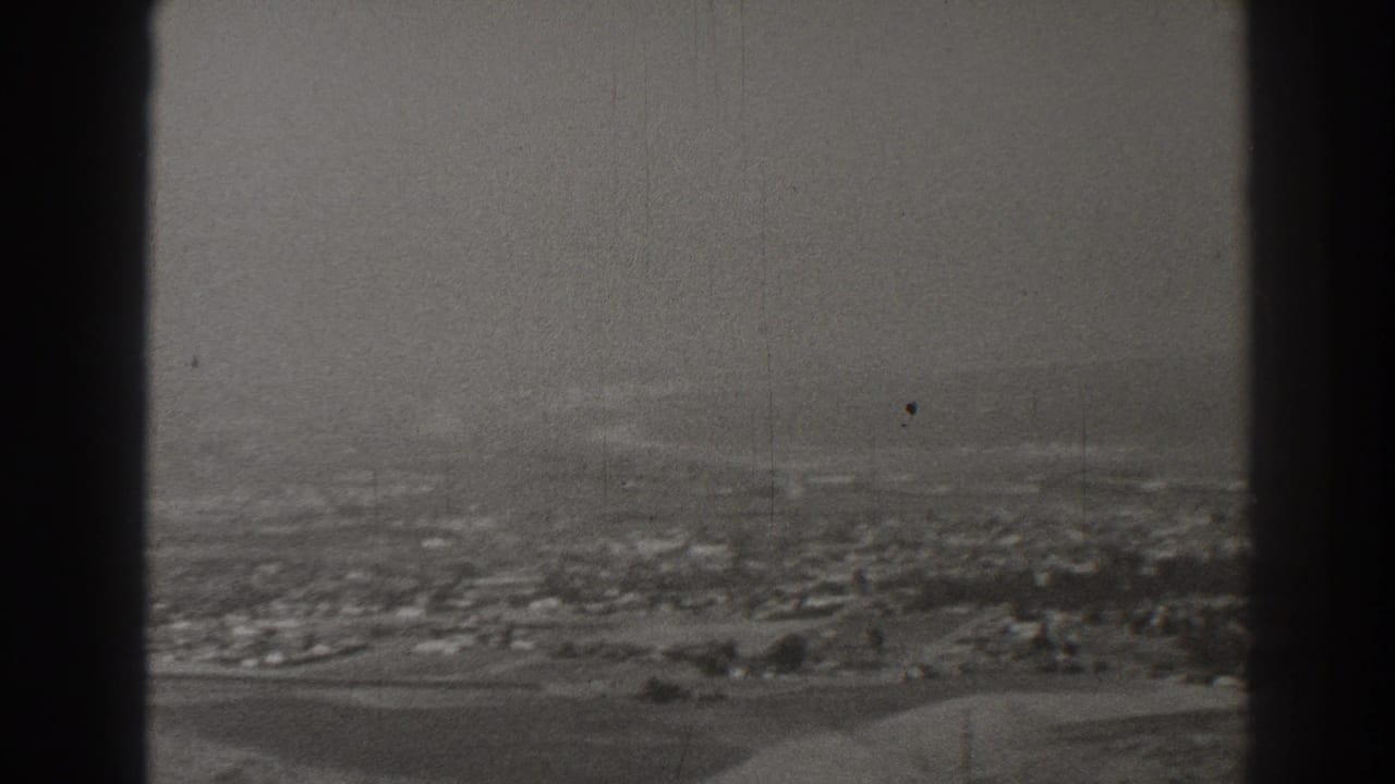 Hazy aerial town view seen through dark aircraft window framing.