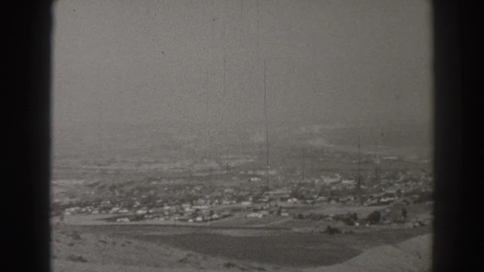 Black-and-white aircraft-window view over Long Beach, California, with scattered low-rise development and open fields under haze.
