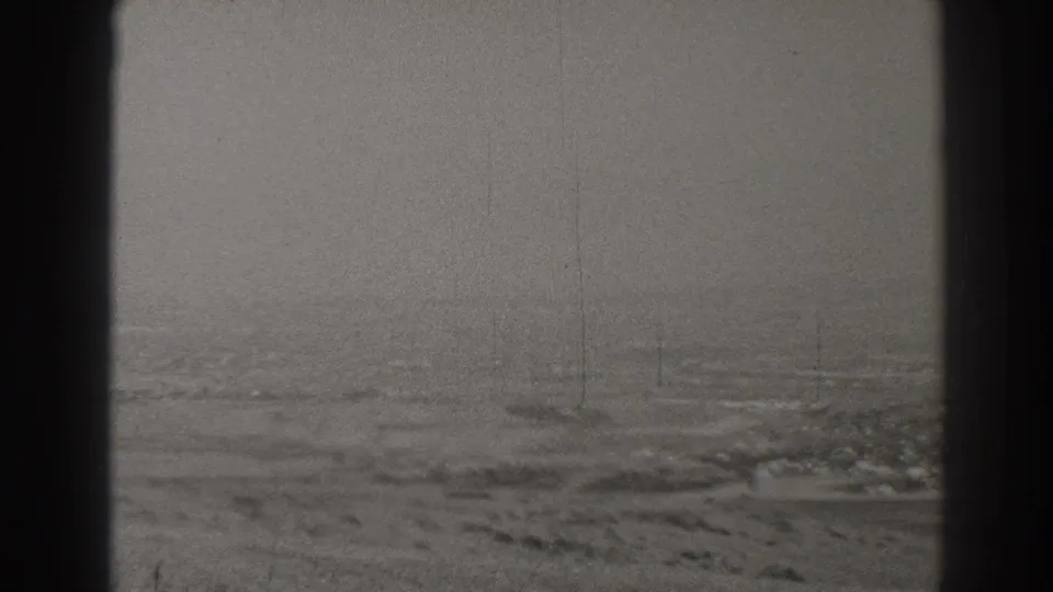 1937 Long Beach area aerial view through an aircraft window, with fog softening distant roads, open ground, and low structures.