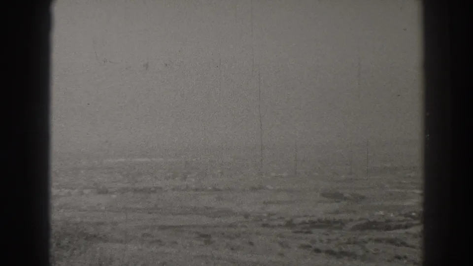 Aerial home-movie frame over the Long Beach area, with haze, faint structures, open land, and dark aircraft framing in the foreground.