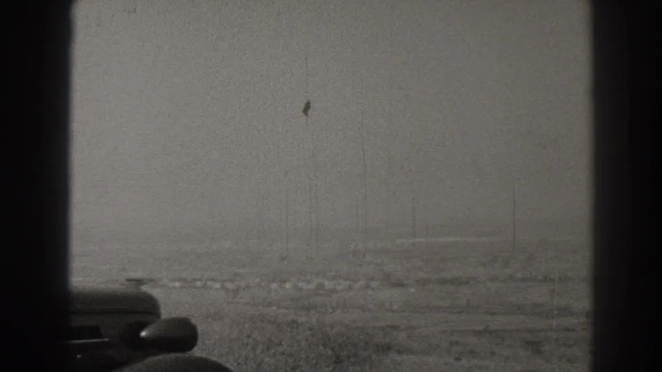 1937 black-and-white 8mm view near Signal Hill, Long Beach, with a car hood and side mirror framing a hazy open landscape.