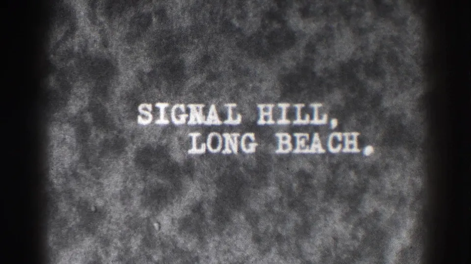 Final black-and-white title-card frame reading Signal Hill, Long Beach, with visible gate edges and dense 8mm grain.